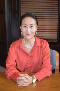 Dr. Shim sits at a table with her hands clasped together