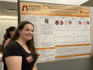 Student posing in front of their research poster on P3b auditory processing differences in adults with and without self-reported attention deficits, SCHOLARS' DAY, April 16th, 2024.